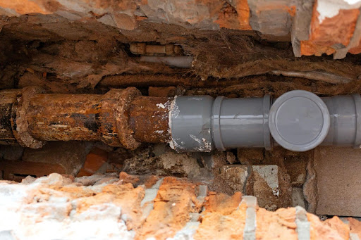 Open trench showing rusted sewer line.